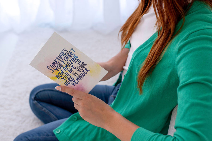 A woman holding a card that says: "sometimes you forget how amazing you are, so here is your reminder"